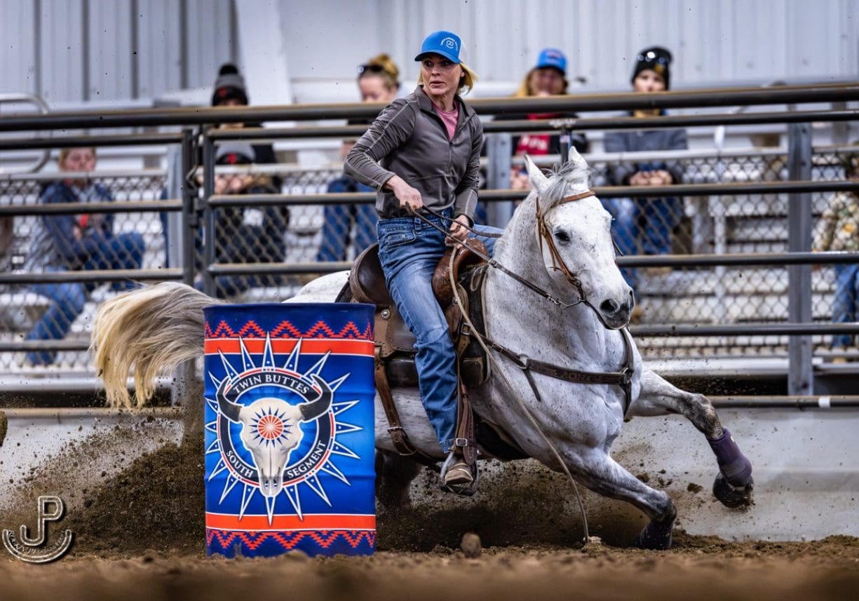 A rider skillfully maneuvers a horse around a colorful barrel in a rodeo event.